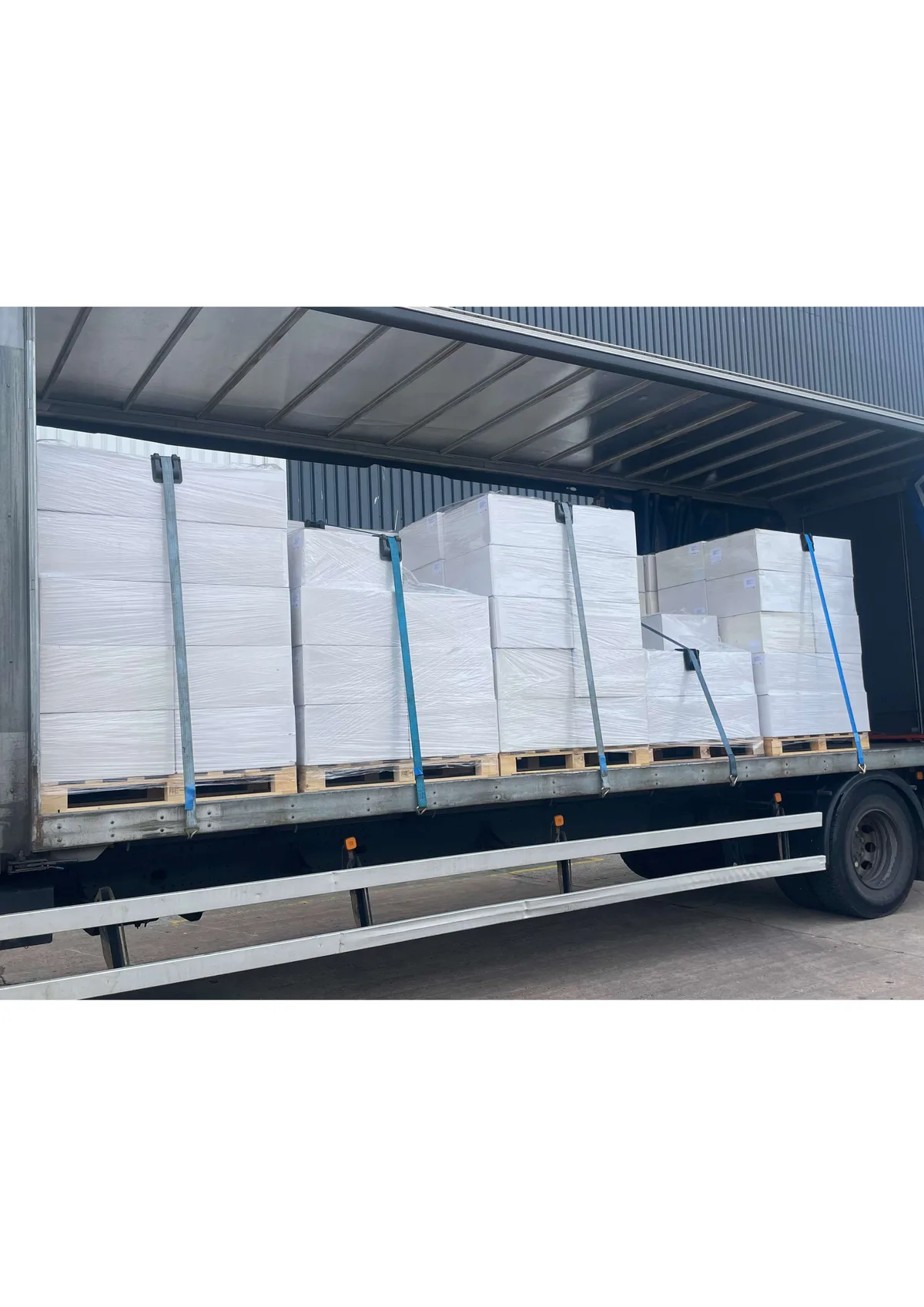 Curtain side lorry with shrink wrapped palletised goods secured with blue straps