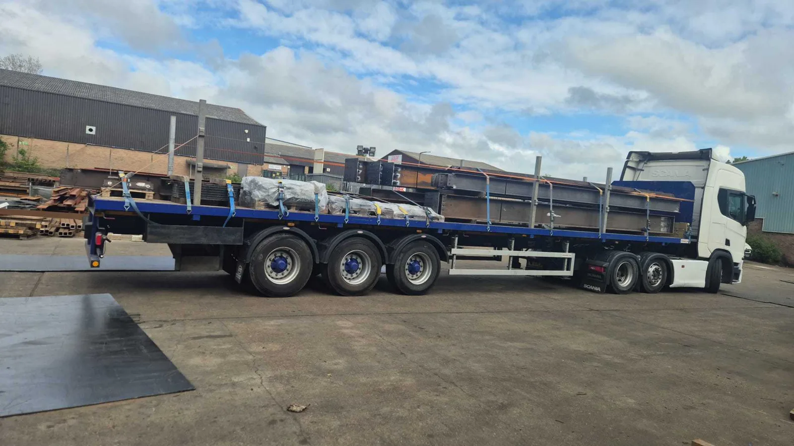 Scania flatbed lorry loaded with oversized steel sections at a collection yard ready for delivery to a City of London construction site