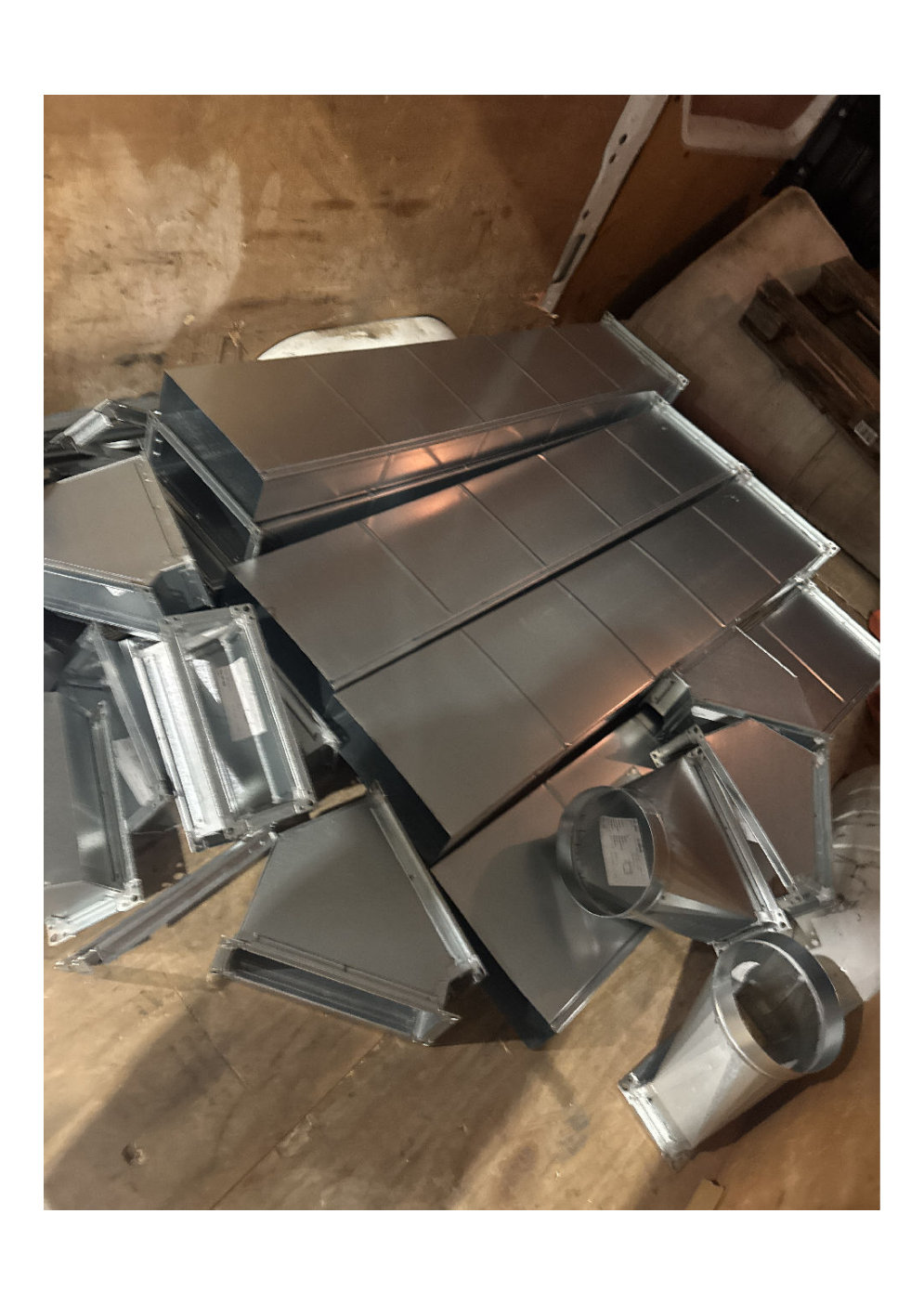 galvanised rectangular HVAC duct sections and fittings stacked on a yard floor ready for loading onto the 18T artic
