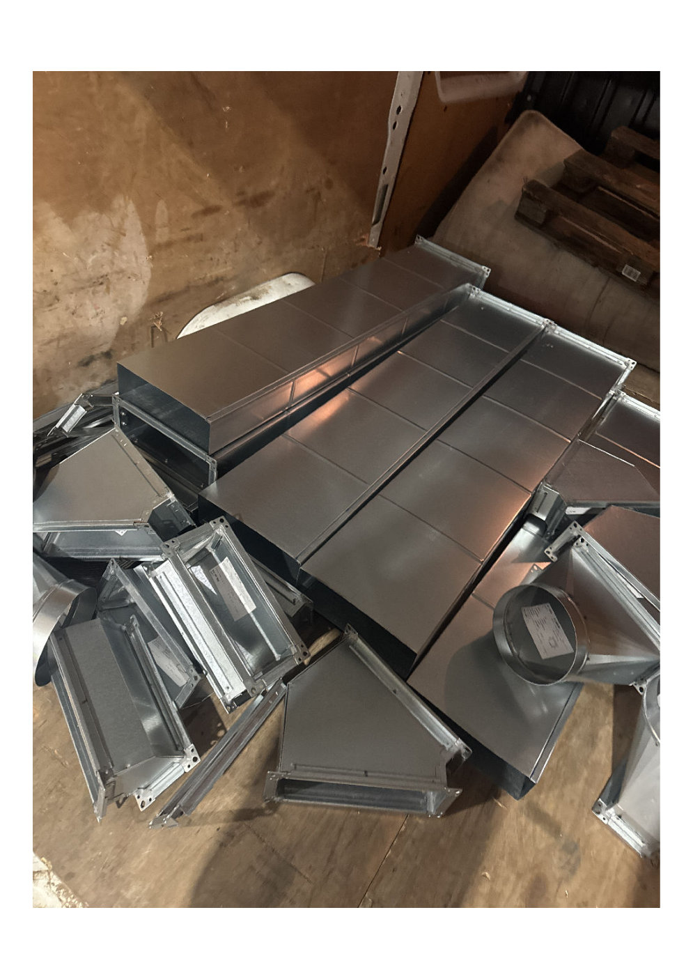 galvanised HVAC ductwork components and fittings arranged on a wooden floor prior to being secured in the artic trailer