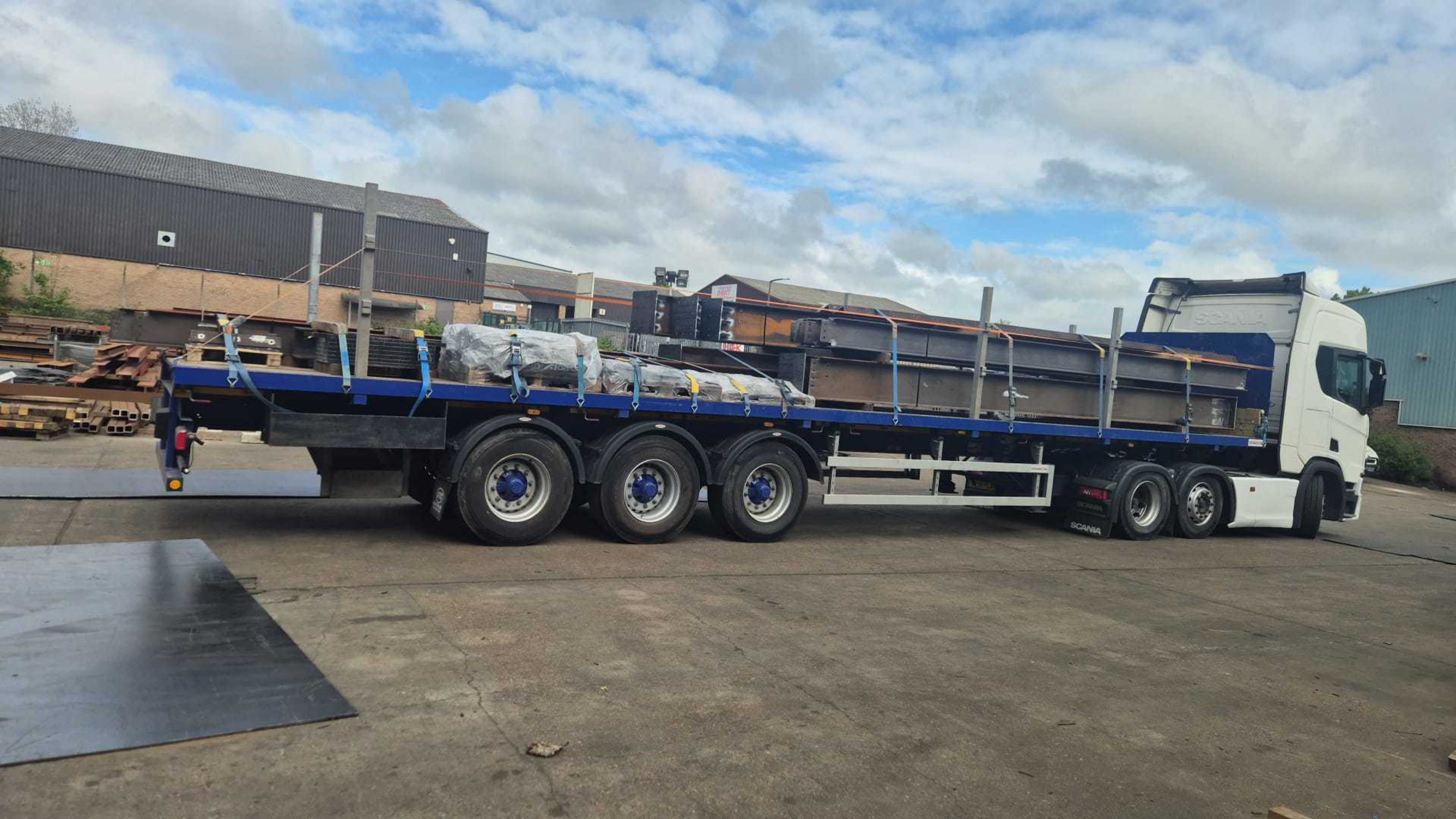 Scania flatbed lorry loaded with oversized steel sections at a collection yard ready for delivery to a City of London construction site